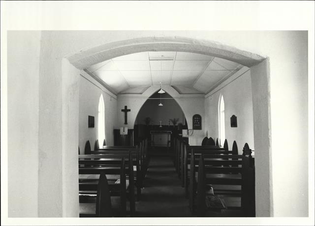 Interior elevation facing the altar and cross with pews in the foreground, throu