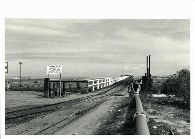 View of jetty at merge with road looking out to sea