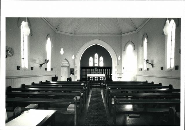 Interior landscape view with pews in the foreground looking towards the altar