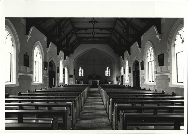 Interior view of church facing altar with pews in foreground