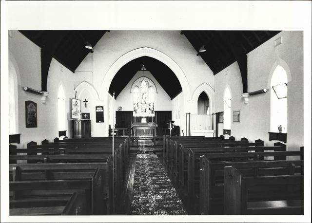 Interior view of church from entrance showing altar in background and pews in fo