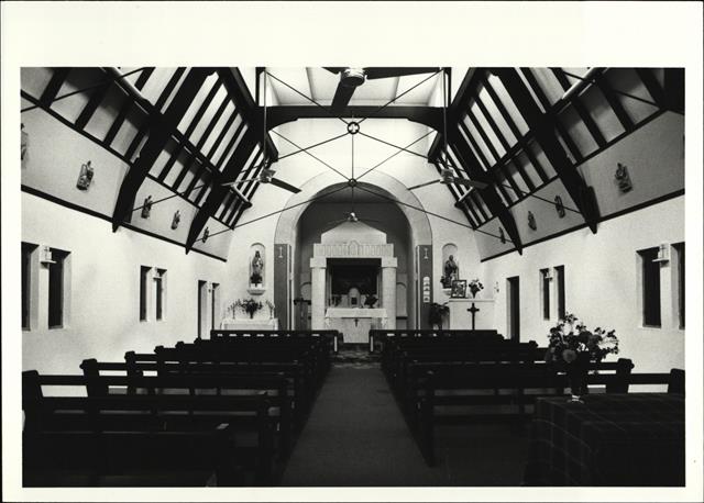 Interior view of church from main entrance showing pews altar and ceiling beams
