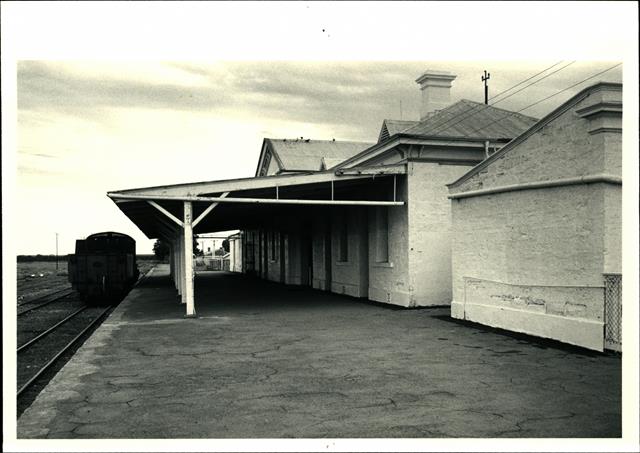 Station platform elevation with rails and a rail car to the left
