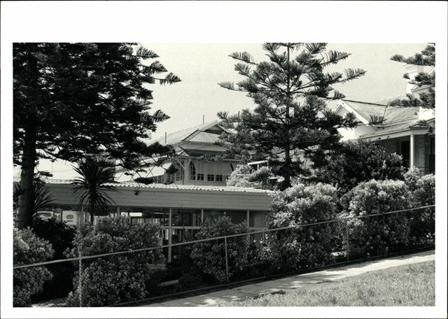 Front corner elevation, obscured by vegetation