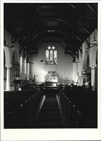 Interior view from entrance showing altar, pews, pulpit and ceiling beams