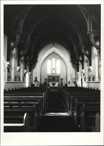 Interior view of church nave facing altar with pews in forground