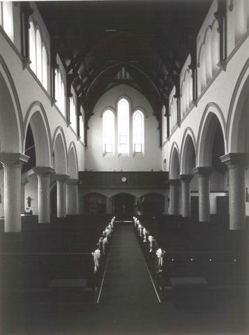 Interior nave from altar end showing pews and stained glass windows